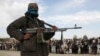 FILE - A member of the Taliban stands with others at the execution of three men in Ghazni Province, April 18, 2015. 