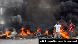 Deux jeunes ivoiriens se tiennent devant une barricade en feu érigée dans le quartier de Koumassi à Abidjan lors des affrontements entre les partisans du candidat de l'opposition Alassane Ouattara et ceux du président sortant Laurent Gbagbo qui refusent de céder le pouvoir, Abidjan, Côte d'Ivoire, 6 décembre 2010.