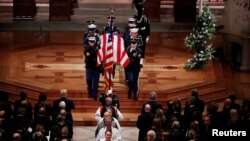 Des membres du clergé et une garde d'honneur militaire portant le cercueil drapé du drapeau partent à la fin des funérailles d'État de l'ancien président George H.W. Bush dans la cathédrale nationale de Washington, le 5 décembre 2018.