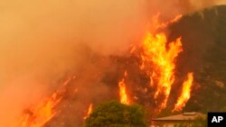 Les flammes se lèvent derrière une maison à Santa Barbara, Californie, 14 décembre 2017.
