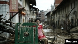 Une femme est assise sur les ruines après le passage du typhon Nepartak qui a balayé le comté de Minqing dans la province du Fujian, en Chine, 10 juillet, 2016. REUTERS / Stringer REUTERS 
