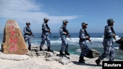 中國海軍軍人2016年1月29日在帕拉塞爾群島（中方稱西沙群島）的伍迪島（中方稱永興島）巡邏。岩石上的文字是“西沙老龍頭”，這是該島附近一堆岩石的名稱。