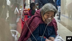 2023年1月5日，一名老年病患在北京急診病房走廊帶著呼吸器接受靜脈注射。 (美聯社照片)