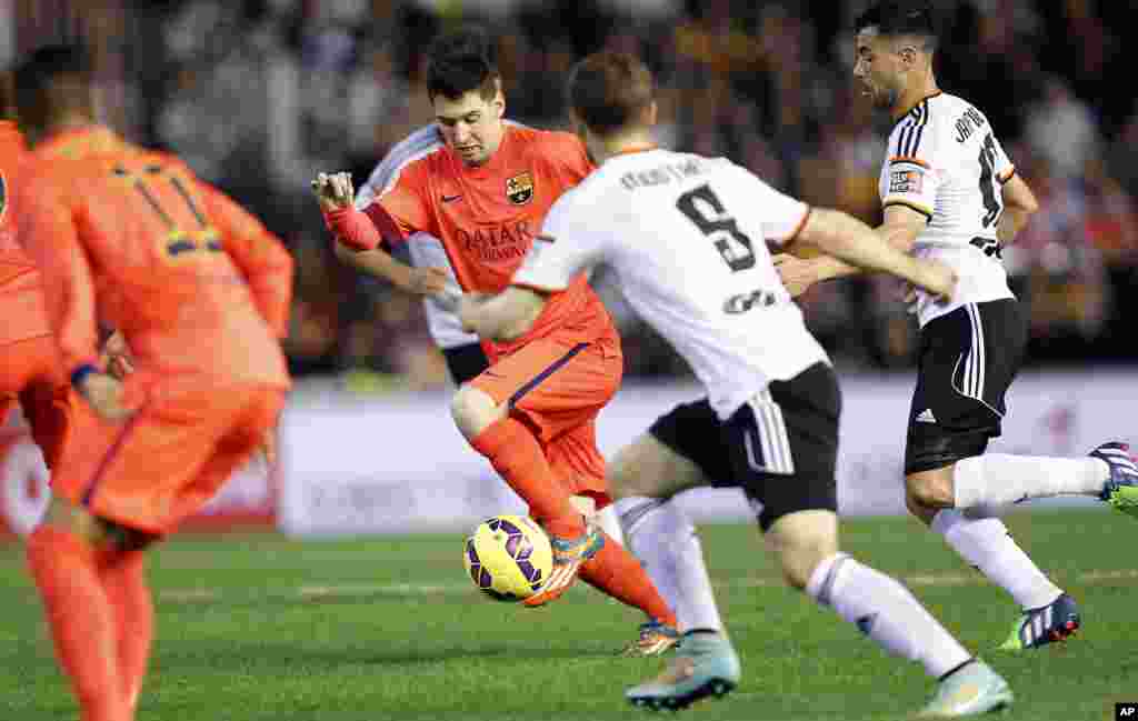 L'Argentin Lionel Messi de Barcelone fait une passe à Mustafi de Valence lors d'un match de football de La Liga espagnole au stade Mestalla à Valence, en Espagne, le dimanche 30 novembre 2014.