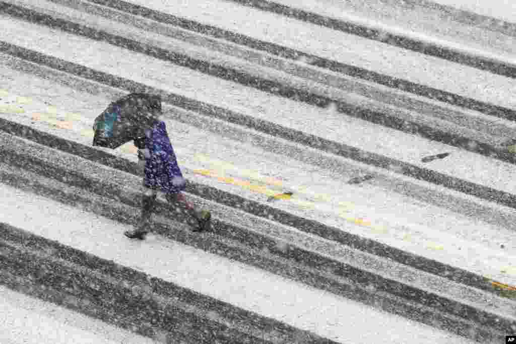 Un piéton traverse la rue couverte de neige lors d'une tempête de neige, à Washington, le 21 mars 2018.