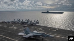美國海軍提供的照片顯示一架超級大黃蜂戰鬥機在行駛在南中國海的里根號航空母艦甲板上著陸，旁邊為尼米茲號航空母艦。(2020年7月6日)