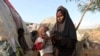 FILE - Rukia Nur feeds her child outside her makeshift dwelling after fleeing famine in the Marka Lower Shebbele regions to the capital Mogadishu.