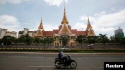 អ្នក​បើក​ម៉ូតូ​ម្នាក់ បើកម៉ូតូ​ខាងមុខ​​​អគារ​វិមាន​រដ្ឋសភា​ជាតិ​នៅ​រាជធានី​ភ្នំពេញ​កាល​ពី​ថ្ងៃ​ទី​២៦ ខែ​សីហា ឆ្នាំ​២០១៤។ (REUTERS)