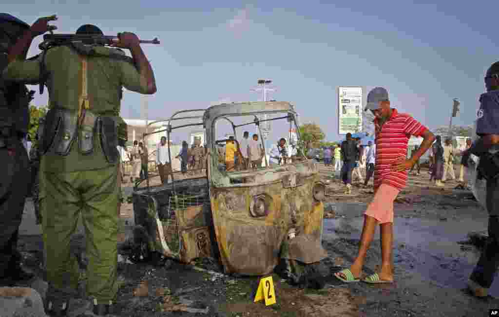 Des soldats somaliens se tiennent près de l'épave d'une moto sur les lieux de explosion en Somalie, le 25 mars 2018.