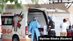 Des agents de santé discutent près d'une ambulance sur le parking de l'hôpital académique Steve Biko à Pretoria, en Afrique du Sud, le 11 janvier 2021.