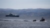 A rescue boat escorts a dinghy with migrants from Afghanistan as a Frontex vessel patrols in the background, on the island of Lesbos, Greece, February 28, 2020.