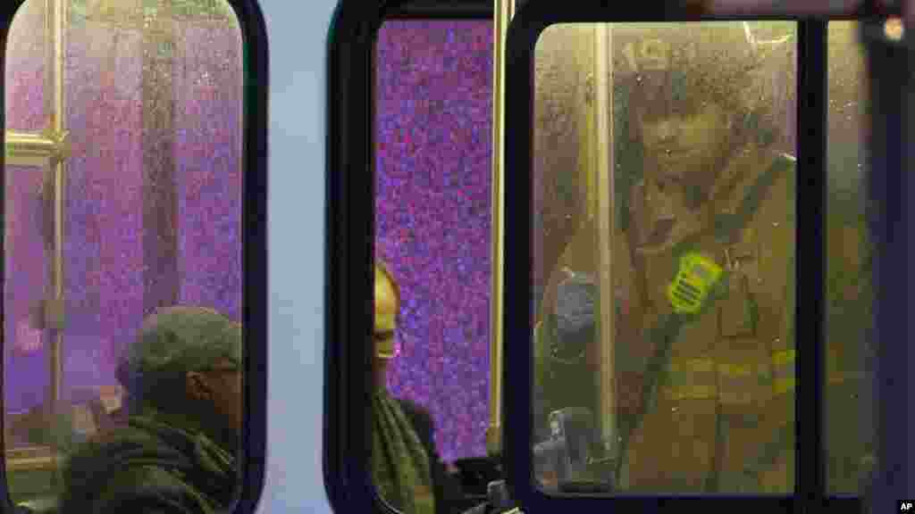 Un pompier assiste les passagers dans un bus après que ces derniers ont été évacués d'un tunnel de métro enfumé à Washington, lundi 12 janvier 2015.