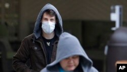 一個戴著口罩的男子從華盛頓州柯克蘭市生命護理中心的入口離開（2020年3月3日）。