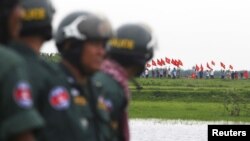 រូប​ឯកសារ៖ មន្ត្រី​ប៉ូលិស​កម្ពុជា​ឈរ​យាម​ខណៈ​ដែល​ពលរដ្ឋ​វៀតណាម​គ្រវី​ទង់ជាតិ​វៀតណាម​នៅ​ត្រើយ​ម្ខាង​ទៀត​នៃ​ព្រែក​មួយ​ ក្នុង​អំឡុង​ពេល​​ទស្សនកិច្ច​​ចុះ​ត្រួត​ពិនិត្យ​ព្រំដែន​​របស់​គណបក្ស​សង្គ្រោះ​ជាតិ​នៅ​ខេត្ត​ស្វាយរៀង​កាល​ពី​ថ្ងៃ​ទី​១៩ ខែ​កក្កដា ឆ្នាំ​២០១៥។