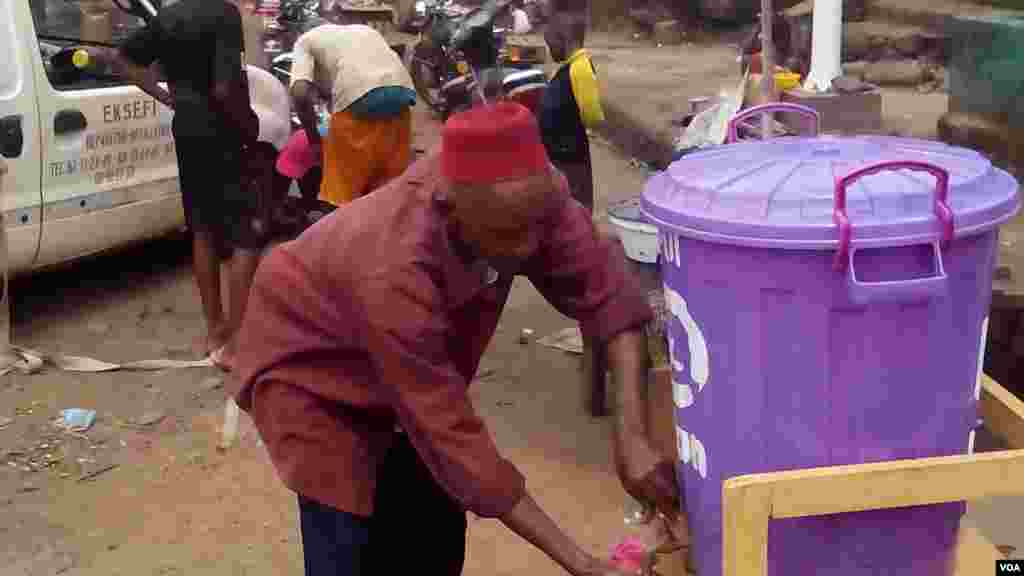 Cet homme se lave les mains en plein marché. La sensibilisation pour une hygiène de tous est nécessaire pour contrer Ebola. (AP Photo).