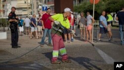 Un agent de la municipalité nettoie le pavement près des policiers déployés sur le lieu de l’attaque à Cambrils, Espagne, 18 août 2017.