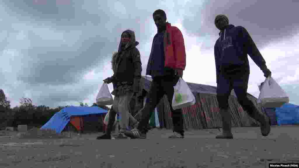 Des migrants marchent dans la "jungle". Ce camp est situé aux abords de Calais dans le nord de la France, 14 octobre 2015 (Nicolas Pinault/VOA).