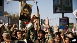 Un rebelle chiite connu comme un Houthi, deuxième à gauche, tient une affiche du chef du Hezbollah, cheikh Hassan Nasrallah alors qu’il assiste avec ses camarades une manifestation pour dénoncer l'agression Arabie à Sanaa, au Yémen, le 22 Avril 2015.