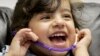 FILE - Three-year-old Amina of Iraq laughs during a hearing test. The WHO reports 360 million people around the globe suffer from disabling hearing loss and that nearly 32 million are children.