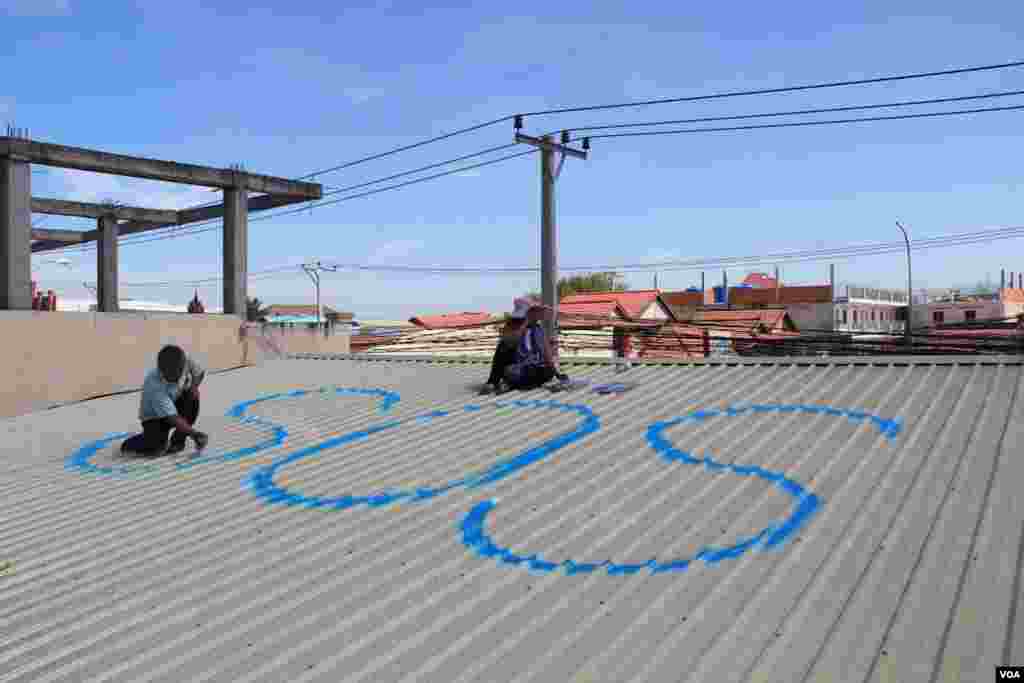 People in Tropeang Lavear display SOS messages on their roofs, which lies in the flight path to Phnom Penh international airport, Cambodia, November 13, 2014. (Nov Povleakhena/VOA Khmer)