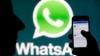 FILE - A WhatsApp logo is seen behind a smartphone, Feb. 20, 2014. Authorities in Afghanistan are temporarily blocking WhatsApp and Telegram social media services in the country.