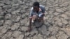 FILE - Last Zimaniwa feels the broken ground at a spot which is usually a reliable water source that has dried up due to lack of rains in the village of Chivi , Zimbabwe, Jan. 29, 2016.