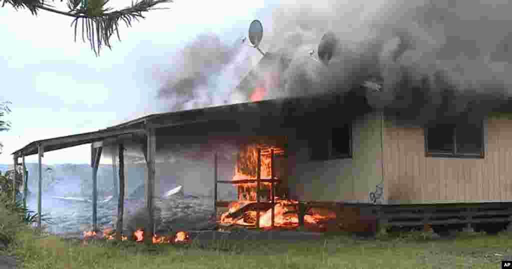Sur cette image prise par le comté d'Hawaii, la coulée de lave du volcan Kilauea brule une structure résidentielle le 11 novembre 2014,à Pahoa, Hawaii.