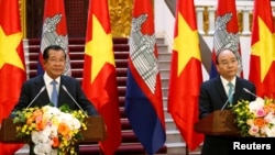 រូប​ឯកសារ៖ លោក​នាយករដ្ឋ​មន្ត្រី ហ៊ុន សែន (ឆ្វេង) និងលោកនាយករដ្ឋមន្ត្រីវៀតណាម ង្វៀន សួនហ៊្វុក (Nguyen Xuan Phuc) ថ្លែងនៅក្នុងសន្និសីទសារព័ត៌មាន​នៅទីក្រុងហាណូយ ប្រទេសវៀតណាម ថ្ងៃទី៧ ខែធ្នូ ឆ្នាំ២០១៨។ 