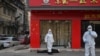 身穿防护服的中国卫生官员在检查一名在武汉一所医院附近倒地死亡的老年男子。（2020年1月30日）