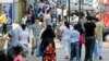 FILE - Shoppers walk in a market in Upton Park, a neighborhood in the British capital's most culturally diverse borough of Newham, in east London June 26, 2010. 