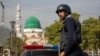 FILE - A Pakistani police officer stands guard outside the Barri Imam shrine, as security is beefed up in the capital following a suicide attack at a Sufi shrine in interior Sindh, Islamabad, Pakistan.