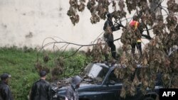 Des pompiers malgaches s'activent pour enlever un arbre tombé sur une voiture pendant le cyclone tropical Enawo à Antananarivo, Madagascar, le 8 mars 2017.