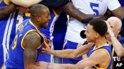 Stephen Curry (30) et Andre Iguodala (9), nouveaux champions de la NBA 2015, célèbrent leur victoire sur les Cavaliers, Cleveland, le 16 juin 2015. (AP Photo/Paul Sancya) 
