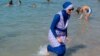 A woman wearing a burkini walks in the water August 27, 2016 on a beach in Marseille, France, the day after the country's highest administrative court suspended a ban on full-body burkini swimsuits that has outraged Muslims and opened divisions within the