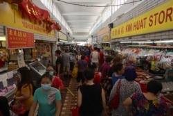 Customers visit a wet market to buy food in Singapore on April 4, 2020, with some people wearing facemasks due to concerns over the spread of the COVID-19 coronavirus.