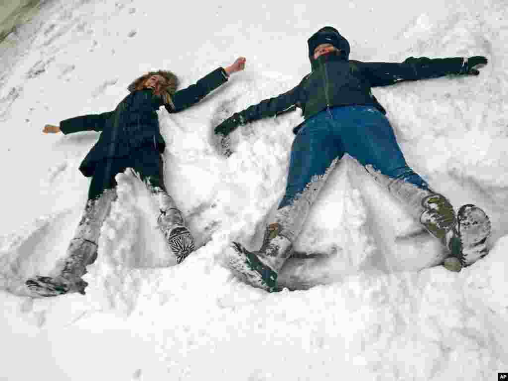 Bianca Hillier, left, of Columbus, Ohio, and Eloise Pollard of London take advantage of a snowtorm travel ban to do something they never envisioned: making snow angels on a normally busy stretch of Manhattan’s Tenth Avenue at West 34th Street in New York, Jan. 27, 2015.