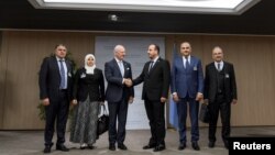 Poignée de main entre le médiateur de l'ONU pour la Syrie, Staffan de Mistura, et le chef du Comité des négociations, Nasser Al-Hariri (3e à partir de la droite), en présence des membres de l'opposition syrienne, à Genève, en Suisse, le 28 novembre 2017.