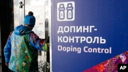 Un homme passe devant une pancarte du contrôle antidopage, au Centre de ski lors des Jeux Olympiques d'hiver de 2014 à Krasnaya Polyana, Russie.