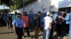 Una policía pasa junto a personas que hacen cola para ingresar a una escuela utilizada como centro de votación, para emitir su papeleta durante las elecciones presidenciales de Nicaragua en Managua, el 7 de noviembre de 2021. 