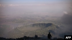 Des volcanologues et des gardes forestiers congolais du parc national des Virunga regardent la vallée du haut du volcan Nyiragongo, au nord de Goma, la capitale provinciale du Nord-Kivu, le 11 juin 2021.