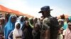 Un personnel de la sécurité fait signe aux réfugiés du camp de Bakkasi pour les déplacés internes après une manifestation contre les rations de nourriture trop petites, à Maiduguri, dans l'État de Borno, Nigeria, le 29 août 2016. 