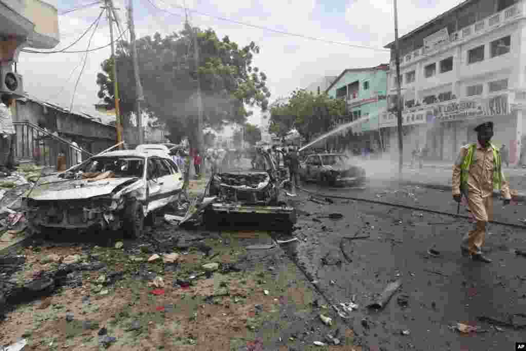 Un soldat somalien patrouille près des voitures détruites après l'attentat près d'un centre commercial à Mogadiscio, en Somalie, le 30 juillet 2017.