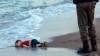 FILE - In this Sept. 2, 2015 photo, a paramilitary police officer investigates the scene before carrying the lifeless body of 3-year-old Aylan Kurdi from the sea shore, near the beach resort of Bodrum, Turkey.