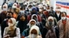Orang-orang yang memakai masker berjalan di peron stasiun kereta api di tengah merebaknya varian Omicron COVID-19 di Jakarta, 3 Januari 2022. (REUTERS/Willy Kurniawan)