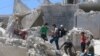 People walk on the rubble of a site hit by a barrel bomb in the rebel held area of Old Aleppo, Syria July 11, 2016. 
