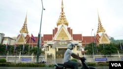 រូបឯកសារ៖ បុរសម្នាក់បើកម៉ូតូកាត់មុខអគាររដ្ឋសភាក្នុងក្រុងភ្នំពេញ កាលពីល្ងាចថ្ងៃទី២ ខែឧសភា ឆ្នាំ២០១៨។ (អូន ឆេងប៉រ/វីអូអេ)