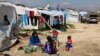 FILE - Syrian women prepare food for their family outside their tents, at a Syrian refugee camp in the town of Bar Elias, in Lebanon's Bekaa Valley, March 29, 2016. 