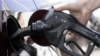 FILE - A consumer purchases gas at a filling station.