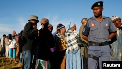 Un policier assure la sécurité près d’une file d’électeurs devant un bureau de vote dans le village de Magkhoakhoeng, près de Maseru, Lesotho, 2 février 2015.