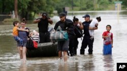 Quelques personnes marchent à travers les eaux de crue après avoir été évacués de leur complexe d'appartements inondés sous l’effet des eaux chaudes El Nino dans le Pacifique, à Houston, 19 avril 2016. (AP Photo / David J. Phillip, File)